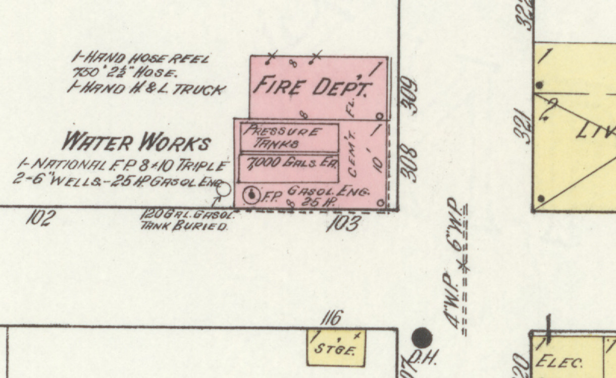A detail from a 1914 fire insurance map. Two small brick buildings stand together on Race Street, one lettered Fire Dept and the other Water Works, with handwritten notes beside them listing a hand hose reel, seven hundred fifty feet of hose, a hook and ladder truck, a National fire pump, two six inch wells and a twenty-five horsepower gasoline engine. Pressure tanks of seven thousand gallons each are drawn inside. A buried gasoline tank is marked in the yard, a hydrant at the street corner, and four inch and six inch water pipe runs along the road.